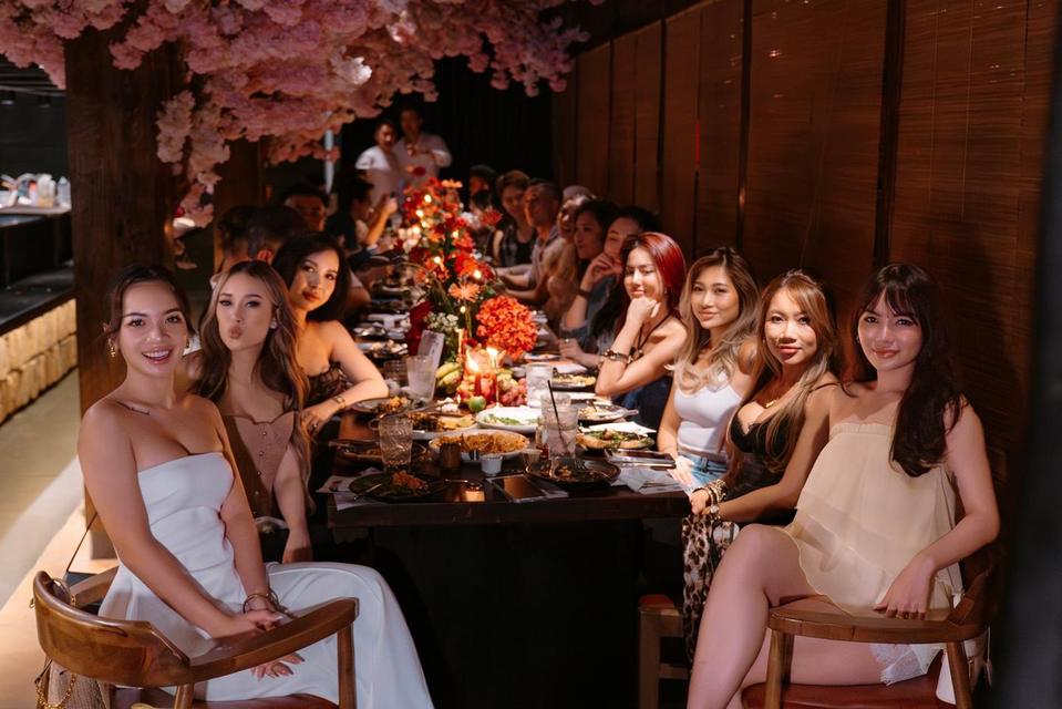 Guests smiling for the camera along the long table under cherry blossom