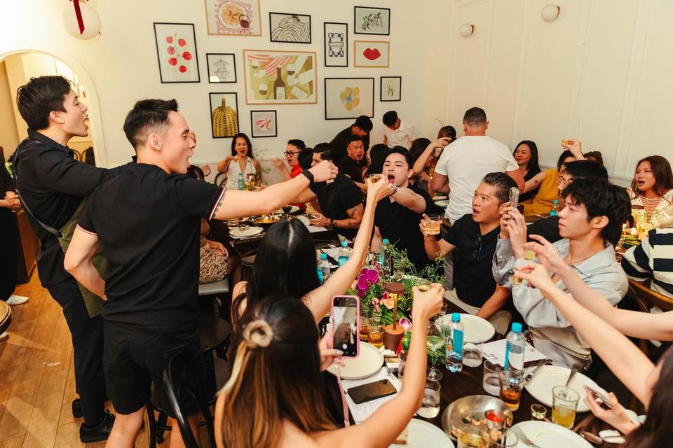 Guests on their feet cheering and filming across a packed table