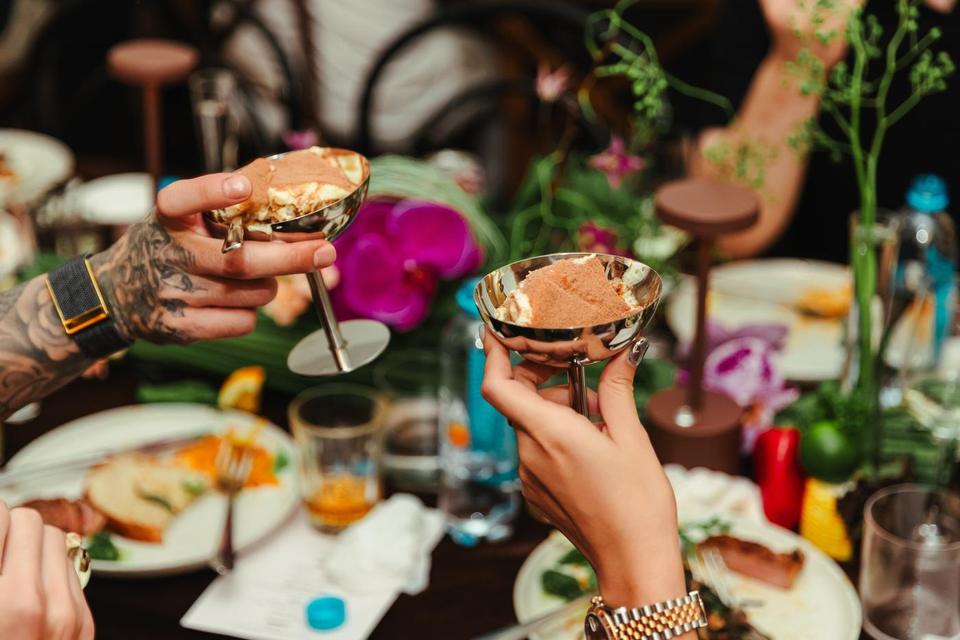 Two guests clinking silver dessert cups over the table