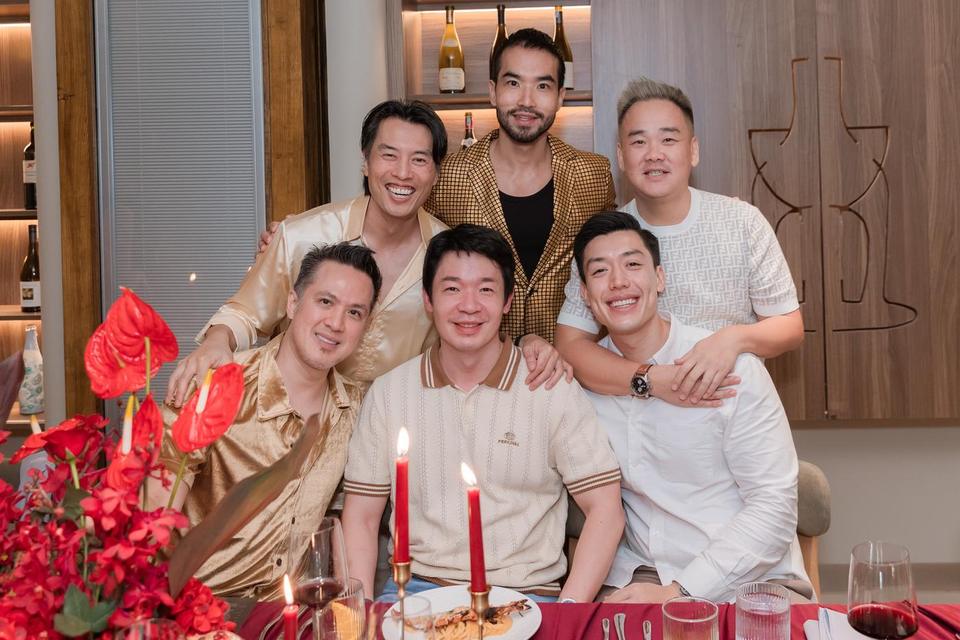 Six friends gathered for a group photo at a candlelit red table