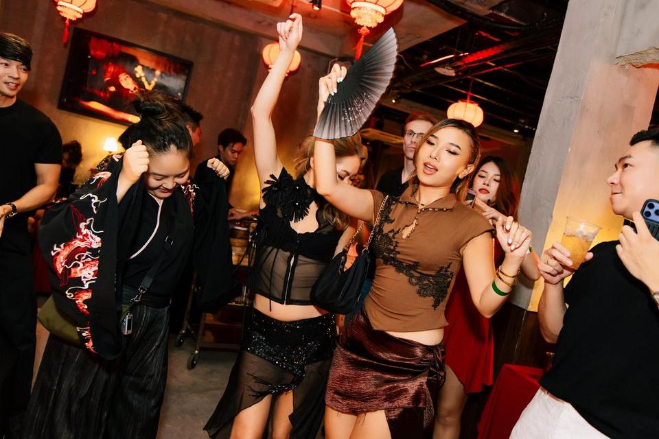 Guests dancing with hand fans under red lanterns at Dim Sum Disco