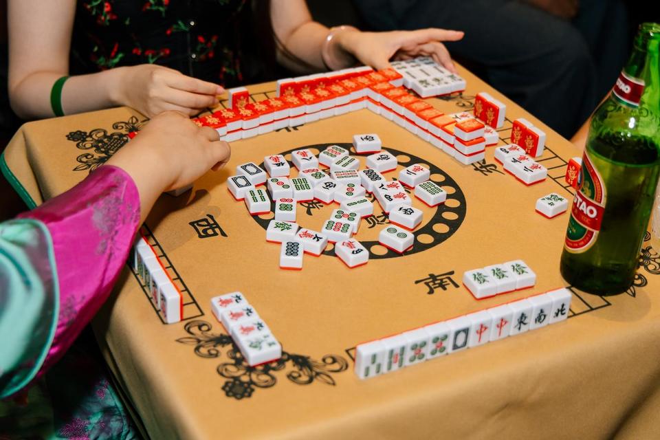 Hands shuffling mahjong tiles on a game table