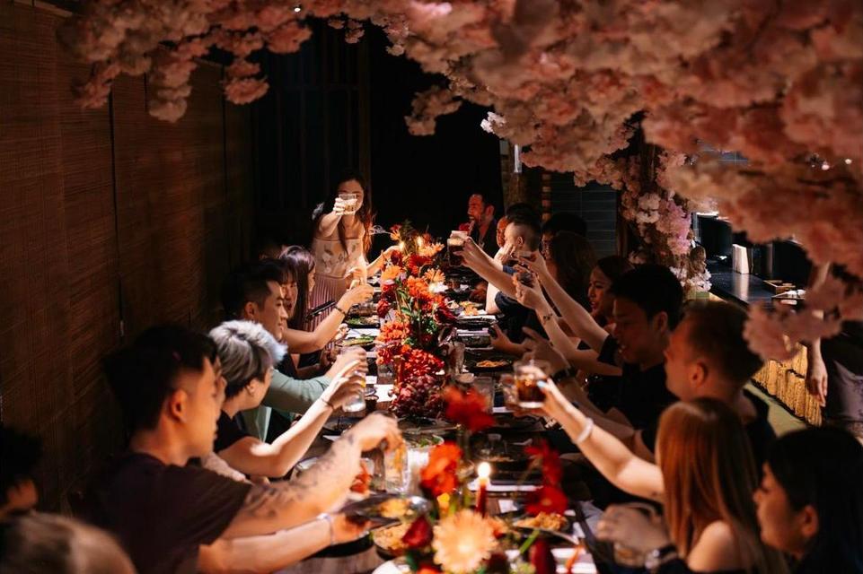 The long table raising glasses under the cherry blossom
