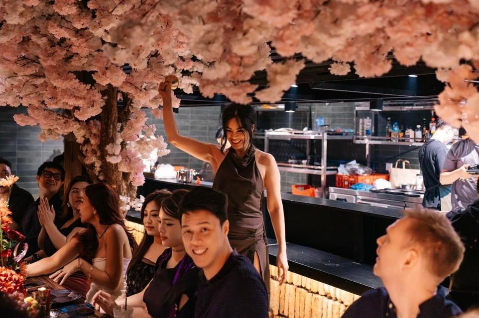 A host ringing the bell under the cherry blossom as guests cheer
