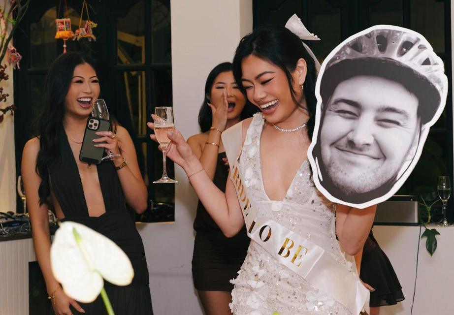 A bride-to-be laughing with friends, holding up a cut-out face