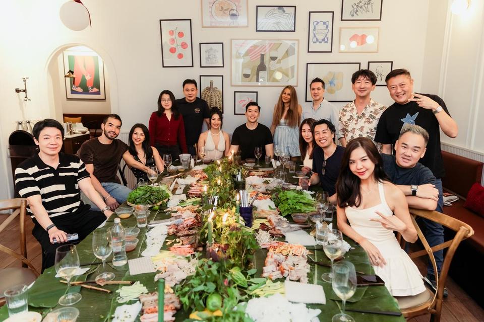Guests gathered around a long candlelit gặp table, smiling for the camera