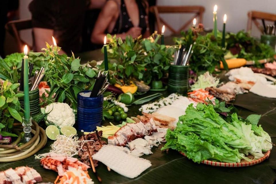 The long table set with candles, fresh herbs, lettuce and grilled meats