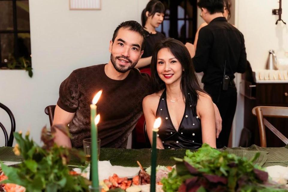 Two guests smiling side by side at the candlelit table