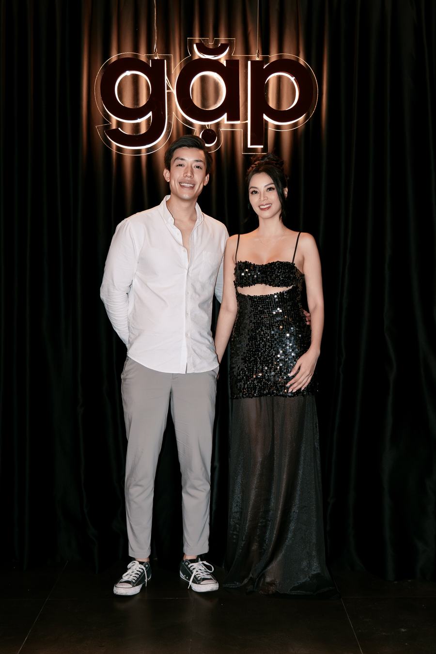 Tam and Huong in front of the glowing gặp sign on opening night