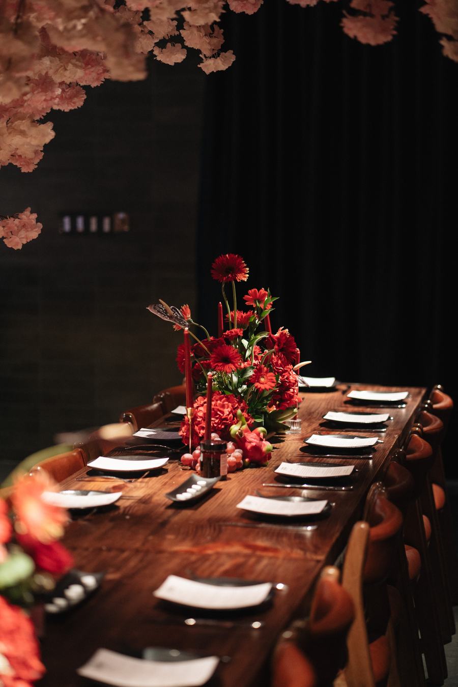 The long table set before guests arrive, with red flowers and cherry blossom overhead